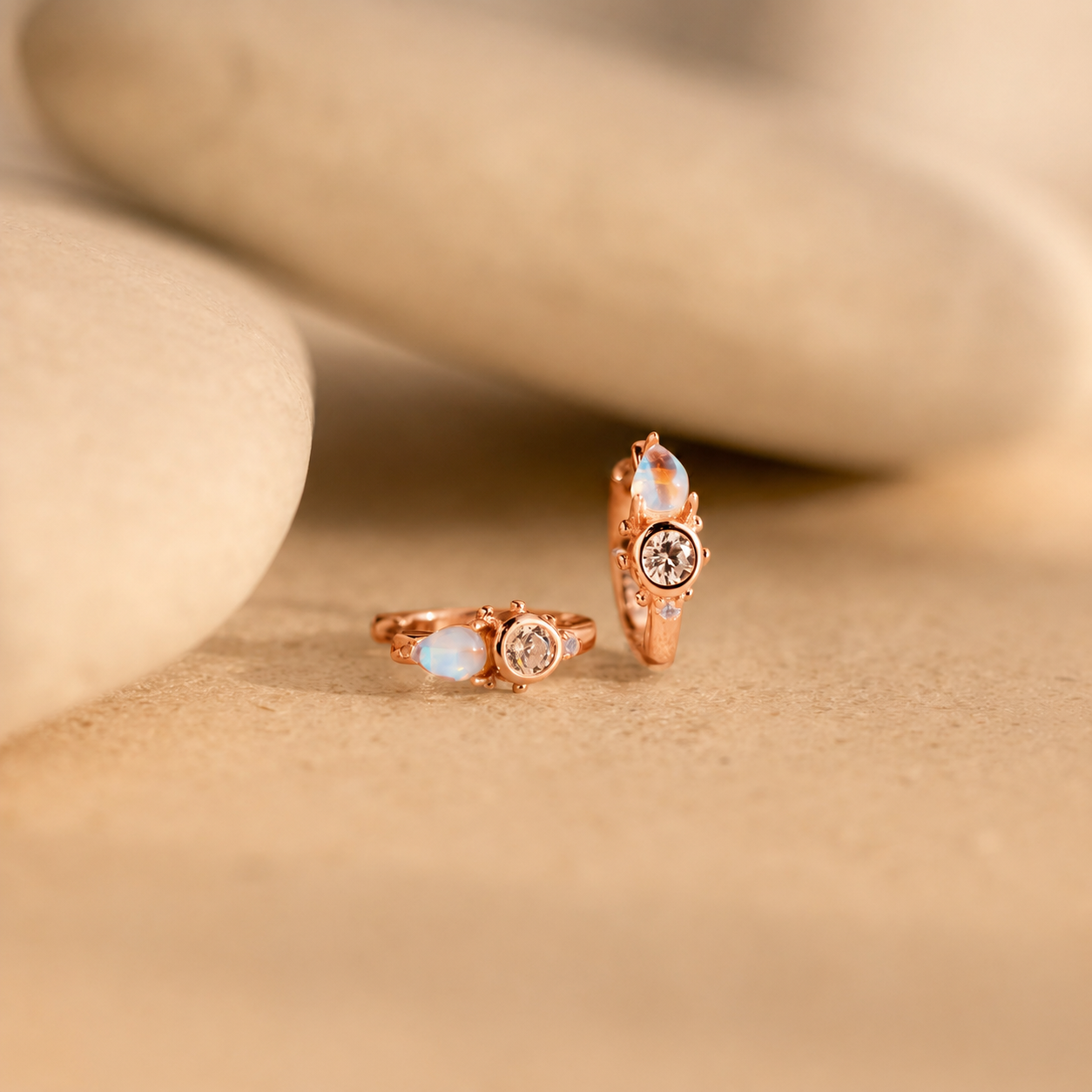 Rose gold rings with gemstones on a beige stone background